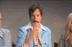 A man with a mustache wearing a blue jacket and a neckerchief is tossing confetti in the air